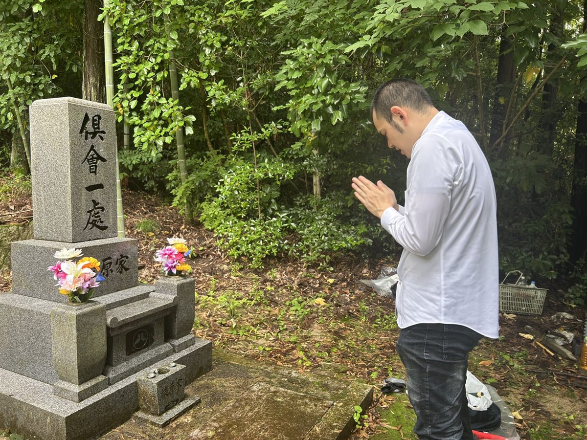 お墓の前で手を合わせる代表